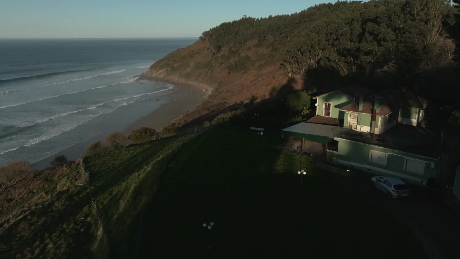 Vista aérea de la casa sobre el acantilado y la costa de Caravia al amanecer